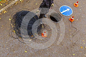 signalman worker pulling an electric cable through the city well