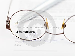 Signature of agreement and pen through eyeglasses