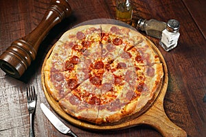 Signature Pepperonis Special Pizza isolated on cutting board top view on table italian fastfood