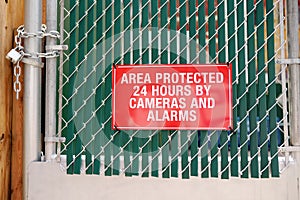 Signboard `Area protected 24 hours by cameras and alarms` on closed by lock gates