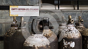 Signboard behind a stack of empty oxygen cylinders in a hospital warehouse