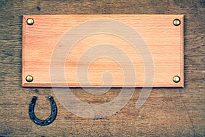Signboard with horse shoe on old wooden wall background