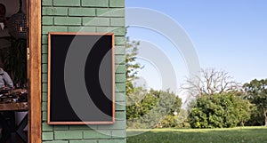 Signboard mockup empty black frame for logo and text on the wood wall and blur garden background