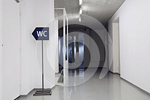 Signboard with wc toilet sign in empty white corridor