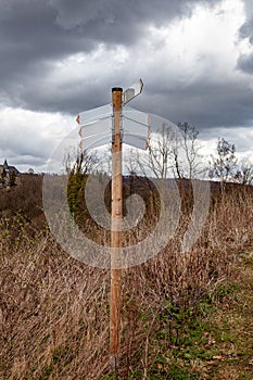A signpost with arrows, which shows the directions of the routes, stands on the slope of the hill photo