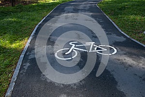 A signpost or bicycle road sign painted on the asphalt in a city park.