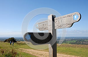 A signpost and a couple walking on the South Downs Way near Brighton in Sussex, England, UK