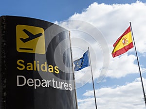 Signpost departure with Spanish and European flag in background.