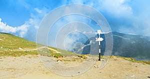 A signpost direction white sign arrow near the tracking path at