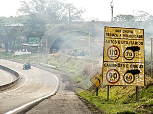 Signpost indicating speed limit on dry and wet roads on Comandante JoÃ£o Ribeiro de Barros Highway