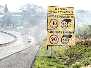 Signpost indicating speed limit on dry and wet roads on Comandante JoÃ£o Ribeiro de Barros Highway