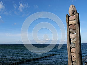 Signpost made of wood and stones at the pier in Zingst on the Darß and a view of the Baltic Sea