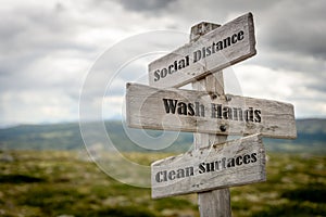 Signpost outdoors with the text social distance, wash hands and clean surfaces to illustrate three basic rules for people to follo