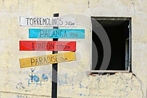 Signpost with plates with inscriptions about the distances to different cities and paradise