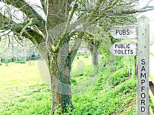 A signpost in Sampford Peverell, Devon, directing towards pubs and toilets