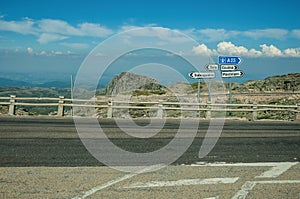 Signposts with town directions on road crossing rocky landscape