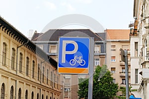 Signs of bicycle parking on background of city. Inscription parking on metallic blue plate