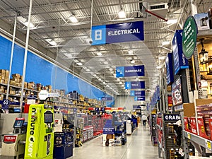 The signs hanging from the ceiling at Lowes home improvement store that designate what departments are in the aisle while people
