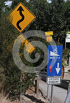 Signs informing cyclists to dismount and warning wheelchair users of steep and winding path photo
