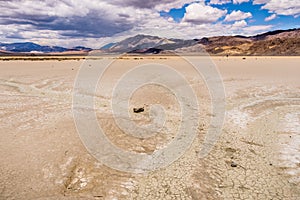 Signs of streams of running water at the Racetrack Playa; mountains and clouds scenery in the background; Death Valley National