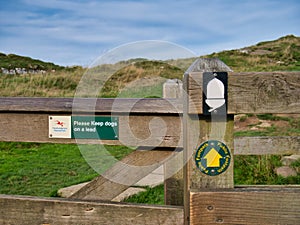 Signs on a weathered wooden gatepost show the way of Hadrian`s Wall Path in the Northumberland National Park, UK.