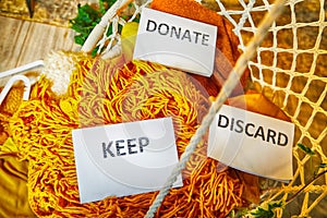 Signs with the words keep, donate, discard and fashion clothes folded in stacks in cozy room. The concept of cluttering