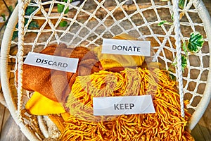 Signs with the words keep, donate, discard and fashion clothes folded in stacks in cozy room. The concept of cluttering