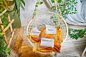 Signs with the words keep, donate, discard and fashion clothes folded in stacks in cozy room. The concept of cluttering