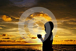 Sihlouette of praying kid during sunset photo