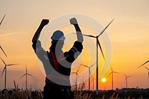 Sihouette back of engineer or technician man raise hands up look like happy action and stand in front of windmill or wind turbine