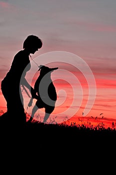 Sihouette of a young woman playing with her dog at