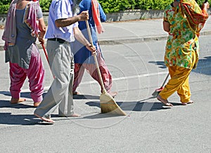 Sikh people while sweeping the street during the religious cerem