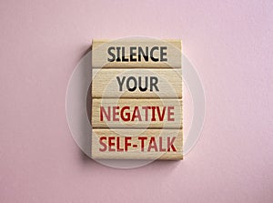Silence your negative self-talk symbol. Concept words Silence your negative self-talk on wooden blocks. Beautiful pink background
