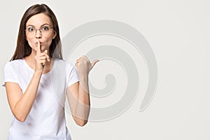 Silent girl holding finger on lips isolated on grey background