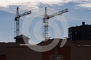 silhoette of tower cranes on construction site, providing housing for low-income citizens of third world countries