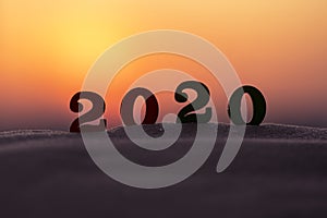 Silhouette of 2020 wooden numbers on the sand on the beach at sunset. Setting sun. The symbol of the outgoing year.
