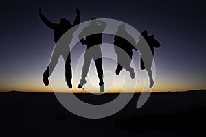 A silhouette of 4 young people jumping