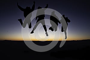 A silhouette of 4 young people jumping