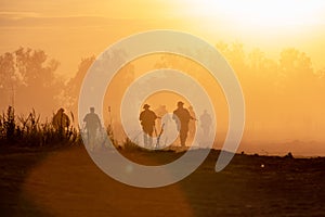 Silhouette action soldiers walking hold weapons the background is smoke and sunset. War, military and danger concept