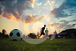 Silhouette action sport outdoors of a group of kids having fun playing soccer football for exercise in community rural area under