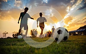 Silhouette action sport outdoors of a group of kids having fun playing soccer football for exercise in community under