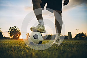 Silhouette action sport outdoors of a young man playing soccer football with the sun