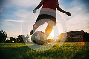Silhouette action sport outdoors of a young man playing soccer football with the sun