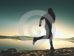 Silhouette of active athlete runner running on sunrise shore. Morning healthy lifestyle exercise