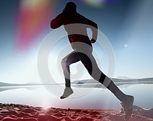 Silhouette of active athlete runner running on sunrise shore. Morning healthy lifestyle exercise