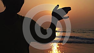 Silhouette of active senior woman practicing tai chi gymnastic on sandy beach.