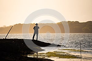 silhouette of an adventurer walking by the seashore and taking pictures, sunset view. motivational concept