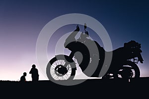 silhouette adventurous motorcycle on blue sunset sky with people, motorcyclists, motorcycle touring background, adventure and