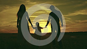 silhouette affectionate parents with child sunset. happy african family sunset park. mother father hold kid hands