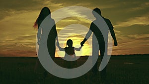 silhouette affectionate parents with child sunset. happy african family sunset park. mother father hold kid hands